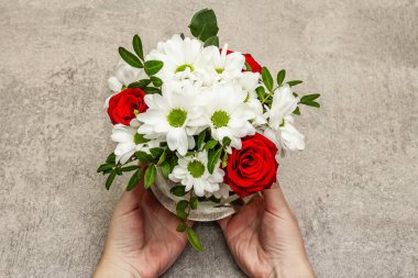 Sevgililer günü ya da düğün ya da doğum günü konsepti. Dişi eller bir buket çiçek tutuyor. Gri taş beton arka plan