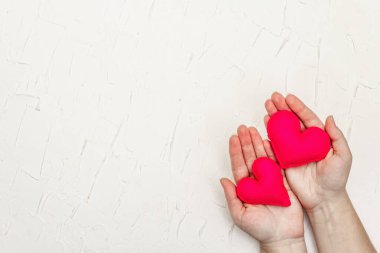 Sevgililer Günü konsepti. Kadın eli, el yapımı keçeli kalp tutuyor. Beyaz macun desenli arkaplan