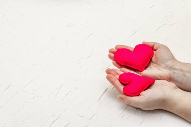 Sevgililer Günü konsepti. Kadın eli, el yapımı keçeli kalp tutuyor. Beyaz macun desenli arkaplan