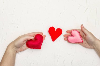 Sevgililer Günü konsepti. Kadın eli, el yapımı keçeli kalp tutuyor. Beyaz macun desenli arkaplan