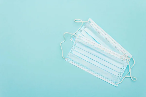 Surgical protection masks isolated on light blue background. Medical products for personal hygiene and the prevention of viral diseases. Coronavirus, COVID-19 pandemic, 2019-nCoV worldwide concept