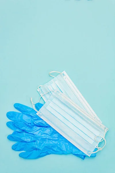 Surgical protection masks and gloves isolated on light blue background. Medical products for personal hygiene and the prevention of viral diseases. Coronavirus, COVID-19 pandemic, 2019-nCoV worldwide concept