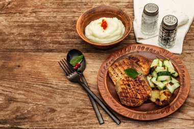 Kızarmış domuz eti, fırında sarımsak, salatalık ve patates püresi. Klasik ahşap masa, siyah çatal bıçak takımı, keten peçete, kopyalama alanı