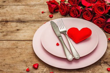 Romantik yemek masası. Sevgililer günü ya da anneler günü için aşk konsepti, düğün çatal bıçak takımı. Bir buket taze burgundy gül, eski ahşap tahta arka plan