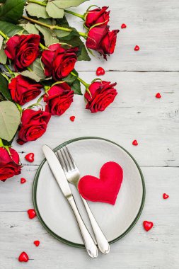 Romantik yemek masası. Sevgililer günü ya da anneler günü için aşk konsepti, düğün çatal bıçak takımı. Bir buket taze burgundy gül, beyaz mahsul tahta arka plan