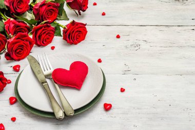 Romantik yemek masası. Sevgililer günü ya da anneler günü için aşk konsepti, düğün çatal bıçak takımı. Bir buket taze burgundy gül, beyaz mahsul tahta arka plan