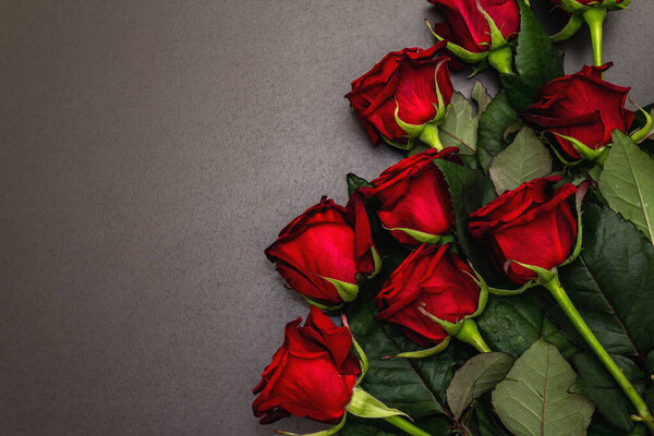 Bouquet of fresh burgundy roses on a black stone concrete background. Fragrant red flowers, gift concept for Valentine's Day, Wedding or Birthday