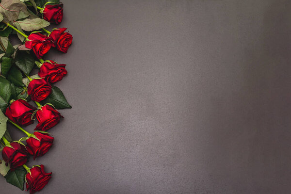 Букет свежих бургундских роз на черном каменном бетонном фоне. Ароматные красные цветы, концепция подарка на День Святого Валентина, свадьбу или день рождения