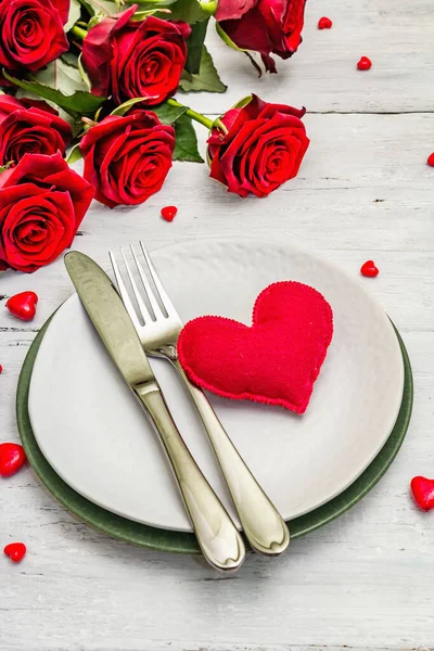 Romantic dinner table. Love concept for Valentine\'s or mother\'s day, wedding cutlery. Bouquet of fresh burgundy roses, white vintage wooden boards background