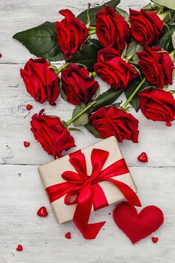 Sevgililer günü tebrik kartı geçmişi hediye kutuları, taze kırmızı güller ve çeşitli kalplerle dolu. Eski beyaz ahşap masa. Düğün ya da doğum günü konsepti, metin yeri, düz yatak