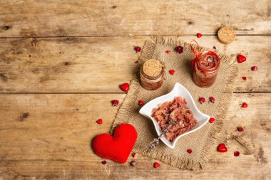 Romantik süslemeli gül yaprağı reçeli. Güzel bir kahvaltı için cam kavanozda ev yapımı tatlı. Sevgililer Günü konsepti, eski ahşap masa