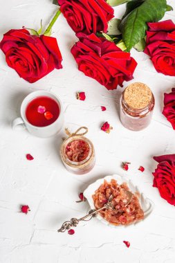 Gül yaprakları reçelli çay saati ve aşıklar için sıcak içecek zamanı. Ev yapımı tatlı kahvaltı, bir buket taze gül, şenlikli dekor. Sevgililer Günü, Düğün veya Doğum Günü konsepti, beyaz alçı arka plan