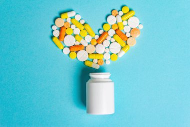Kalp hastalıklarının tedavisi için çeşitli ilaç hapları, haplar ve kapsüller. Kalp şeklinde ve bir şişe hap. Gradyan mavi arkaplan, metin için kopyalama alanı