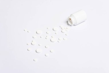 Beyaz ilaç hapları, haplar ve beyaz arka planda izole edilmiş hastalıkların tedavisi için kapsüller. Bir şişe hap, metin için kopyalama alanı