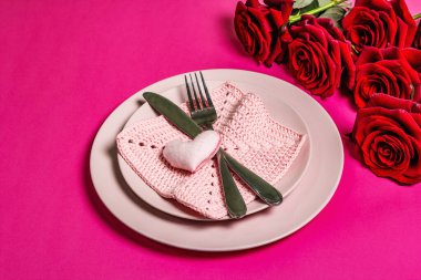 Romantik yemek masası. Sevgililer günü ya da anneler günü için aşk konsepti, düğün çatal bıçak takımı. Bir buket taze burgundy gül, el yapımı örgü peçete.