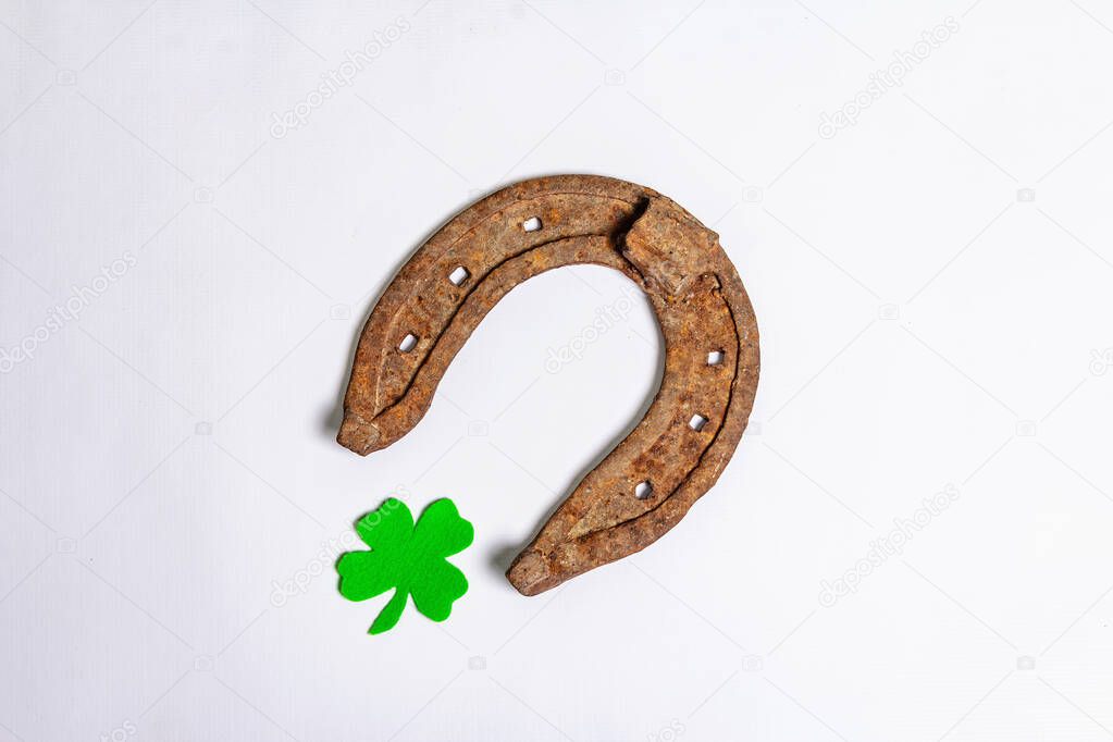 Badly worn horseshoes with a felt clover leaf isolated on white background. Good luck symbol, St.Patrick's day concept