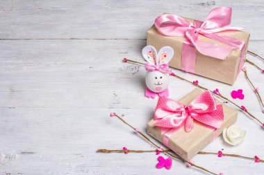 El yapımı geleneksel Paskalya sembolleri. Yumurtadan tatlı bir tavşan, hediye kutusu, pembe tonlarda şenlikli bir dekor. Beyaz tahta arkaplan, boşluğu kopyala