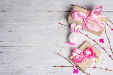 El yapımı geleneksel Paskalya sembolleri. Yumurtadan tatlı bir tavşan, hediye kutusu, pembe tonlarda şenlikli bir dekor. Beyaz ahşap arkaplan, üst görünüm