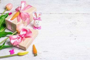 El yapımı geleneksel Paskalya sembolleri. Yumurtadan tatlı bir tavşan, hediye kutusu, pembe tonlarda şenlikli bir dekor. Beyaz tahta arkaplan, boşluğu kopyala