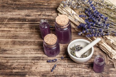 Havanda kurutulmuş lavanta çiçekleri ve bir şişe lavanta yağı ya da eritilmiş su. Eski kitaplar ve lavanta çiçekleri ahşap arka planda toplanmış, metin için yer var.