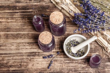 Havanda kurutulmuş lavanta çiçekleri ve bir şişe lavanta yağı ya da eritilmiş su. Eski kitaplar ve lavanta çiçekleri ahşap arka planda, üst tarafta.