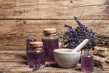 Havanda kurutulmuş lavanta çiçekleri ve bir şişe lavanta yağı ya da eritilmiş su. Eski kitaplar ve lavanta çiçekleri ahşap arka planda toplanmış, metin için yer var.
