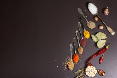 Siyah taş arka planda çeşitli baharatlar, kuru otlar ve sebzeler. Sağlıklı gıda hazırlama konsepti, metin için yer
