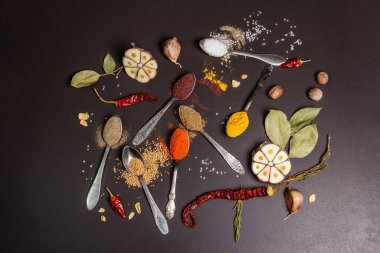 Siyah taş arka planda çeşitli baharatlar, kuru otlar ve sebzeler. Sağlıklı gıda hazırlama konsepti, üst görünüm