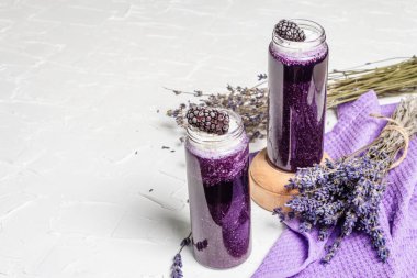 Hindistan cevizi gevreği ve donmuş böğürtlenli lavanta püresi. Kuru çiçek buketi, leylak peçete. Beyaz macun arkaplanı, kopyalama alanı