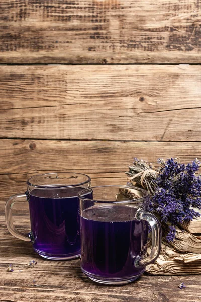Lavender hot tea on vintage wooden table. Natural organic flower drink for morning good mood, old books, dry bouquet, copy space