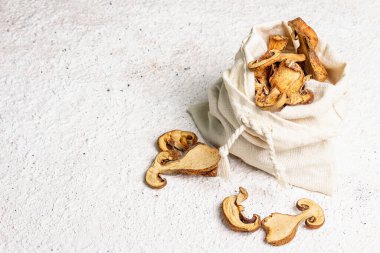 Orman, keten çuvalında kurutulmuş yenilebilir mantar. Susuz dilimler, sağlıklı yemek pişirmek için nefis malzemeler. Açık renk alçı arkaplan, alanı kopyala
