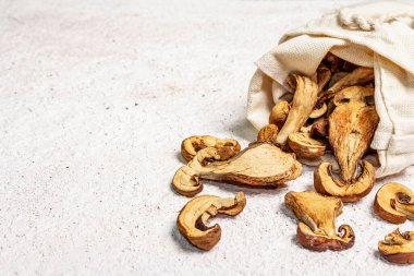 Orman, keten çuvalında kurutulmuş yenilebilir mantar. Susuz dilimler, sağlıklı yemek pişirmek için nefis malzemeler. Açık renk alçı arkaplan, alanı kopyala