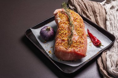 Çiğ domuz filetosu. Sarımsaklı, biberiyeli ve biberli taze et. Siyah taş beton arka plan