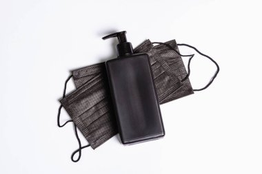 Beyaz arka planda cerrahi koruyucu siyah maskeler ve antiseptik izole edilmiş. Kişisel hijyen ve viral hastalıkların önlenmesi için tıbbi ürünler. Dünya çapında Coronavirus salgını