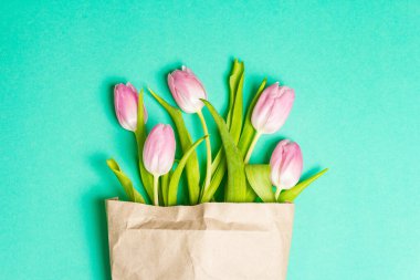 Sıfır atık paketinde bir buket yumuşak pembe lale. Plastik hediye konsepti yok, tebrik kartı var. Paskalya, doğum günü, sevgililer günü ya da anneler günü, düğün tatili turkuaz arka plan