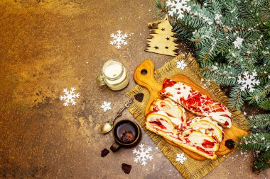 Beyaz çikolatalı ve soslu çilekli turta, sıcak kokulu çay. Noel ağacı ve yeni yıl dekorasyonu, neşeli bir ruh hali. Taş beton zemin, üst görünüm