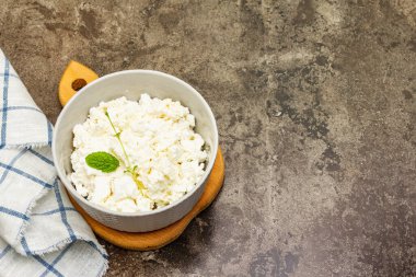 Süt ürünleri, süzme peynir. Vücutta kalsiyum eksikliğinin önlenmesi. Seramik kase, taş beton zemin, üst manzara