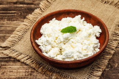 Ev yapımı organik süzme peynir ya da ahşap arka planda kaymak tabakada kaymak. Kapatın.