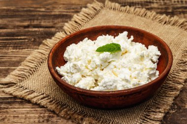 Ev yapımı organik süzme peynir ya da ahşap arka planda kaymak tabakada kaymak. Kapatın.