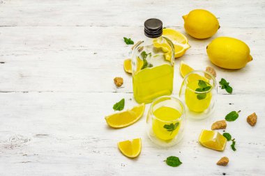 Geleneksel İtalyan sindirimi: limonlu limonata ve kokulu nane yapraklı limoncello. Alkolsüz içecek beyaz tahta tahta arka planda, kopyalama alanı