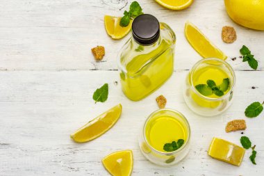 Geleneksel İtalyan sindirimi: limonlu limonata ve kokulu nane yapraklı limoncello. Beyaz tahta arka planda düşük alkollü ferahlatıcı içecek.