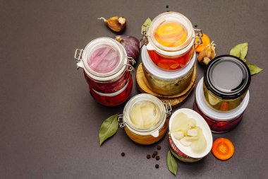 Cam kavanozlarda mayalanmış sebzeler. Mevsimlik sebze konsepti, sağlıklı yaşam tarzı için probiyotik gıdası. Siyah taş arkaplan, üst görünüm