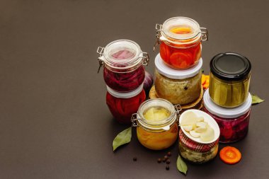 Cam kavanozlarda mayalanmış sebzeler. Mevsimlik sebze konsepti, sağlıklı yaşam tarzı için probiyotik gıdası. Siyah taş arkaplan, boşluğu kopyala