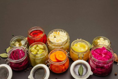 Cam kavanozlarda mayalanmış sebzeler. Mevsimlik sebze konsepti, sağlıklı yaşam tarzı için probiyotik gıdası. Siyah taş arkaplan, boşluğu kopyala