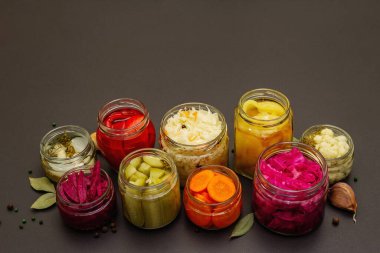 Cam kavanozlarda mayalanmış sebzeler. Mevsimlik sebze konsepti, sağlıklı yaşam tarzı için probiyotik gıdası. Siyah taş arkaplan, boşluğu kopyala