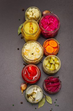Cam kavanozlarda mayalanmış sebzeler. Mevsimlik sebze konsepti, sağlıklı yaşam tarzı için probiyotik gıdası. Siyah taş arkaplan, üst görünüm