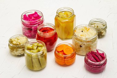 Cam kavanozlarda mayalanmış sebzeler. Mevsimlik sebze konsepti, sağlıklı yaşam tarzı için probiyotik gıdası. Beyaz macun arkaplanı, kopyalama alanı