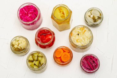 Cam kavanozlarda mayalanmış sebzeler. Mevsimlik sebze konsepti, sağlıklı yaşam tarzı için probiyotik gıdası. Beyaz macun arkaplan, üst görünüm