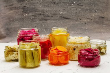 Cam kavanozlarda mayalanmış sebzeler. Mevsimlik sebze konsepti, sağlıklı yaşam tarzı için probiyotik gıdası. Beyaz macun arkaplanı, kopyalama alanı