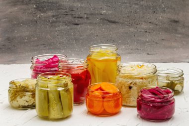 Cam kavanozlarda mayalanmış sebzeler. Mevsimlik sebze konsepti, sağlıklı yaşam tarzı için probiyotik gıdası. Beyaz macun arkaplanı, kopyalama alanı